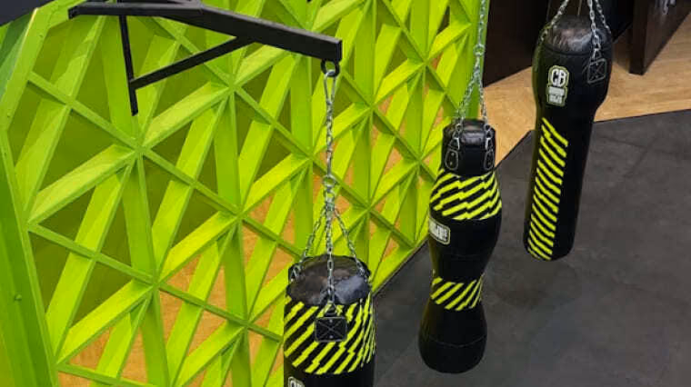 Punch bags beside a bright green geometric feature wall in the Dubai sports club