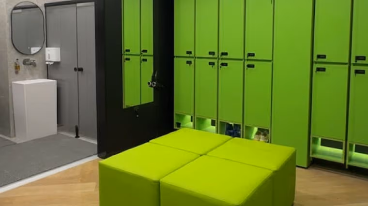 Sports club changing room with green lockers and a matching bench