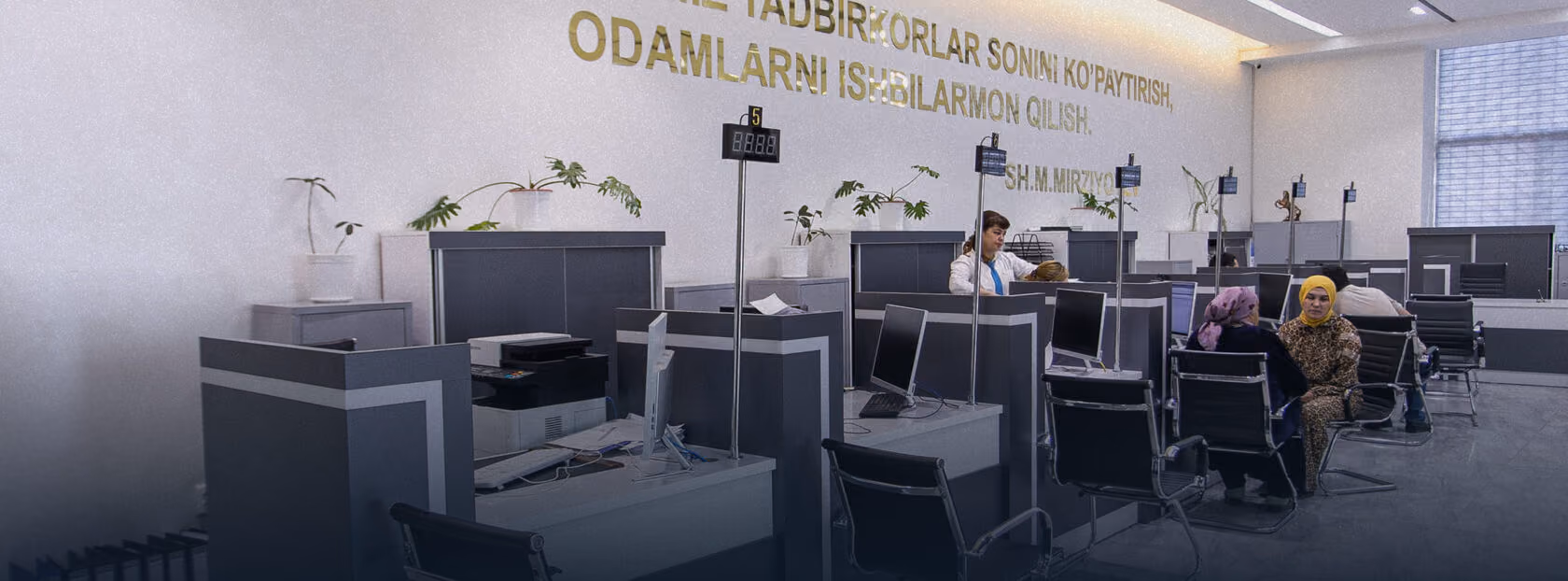 Stollar, kompyuterlar va shisha toʻsiqlarga ega Oʻzbekistondagi Xalq Bank mijozlarga xizmat koʻrsatish zonasi