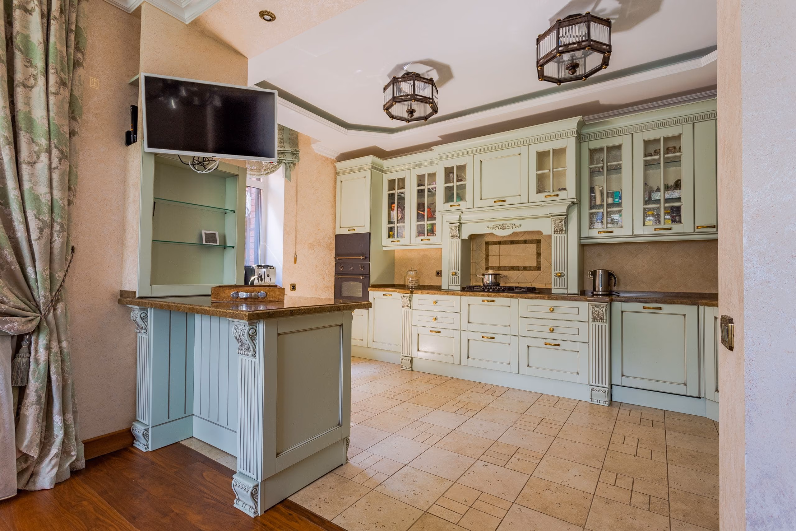 Classic kitchen with pale green framed cabinets, ornate corbels, cornices and a tiled floor
