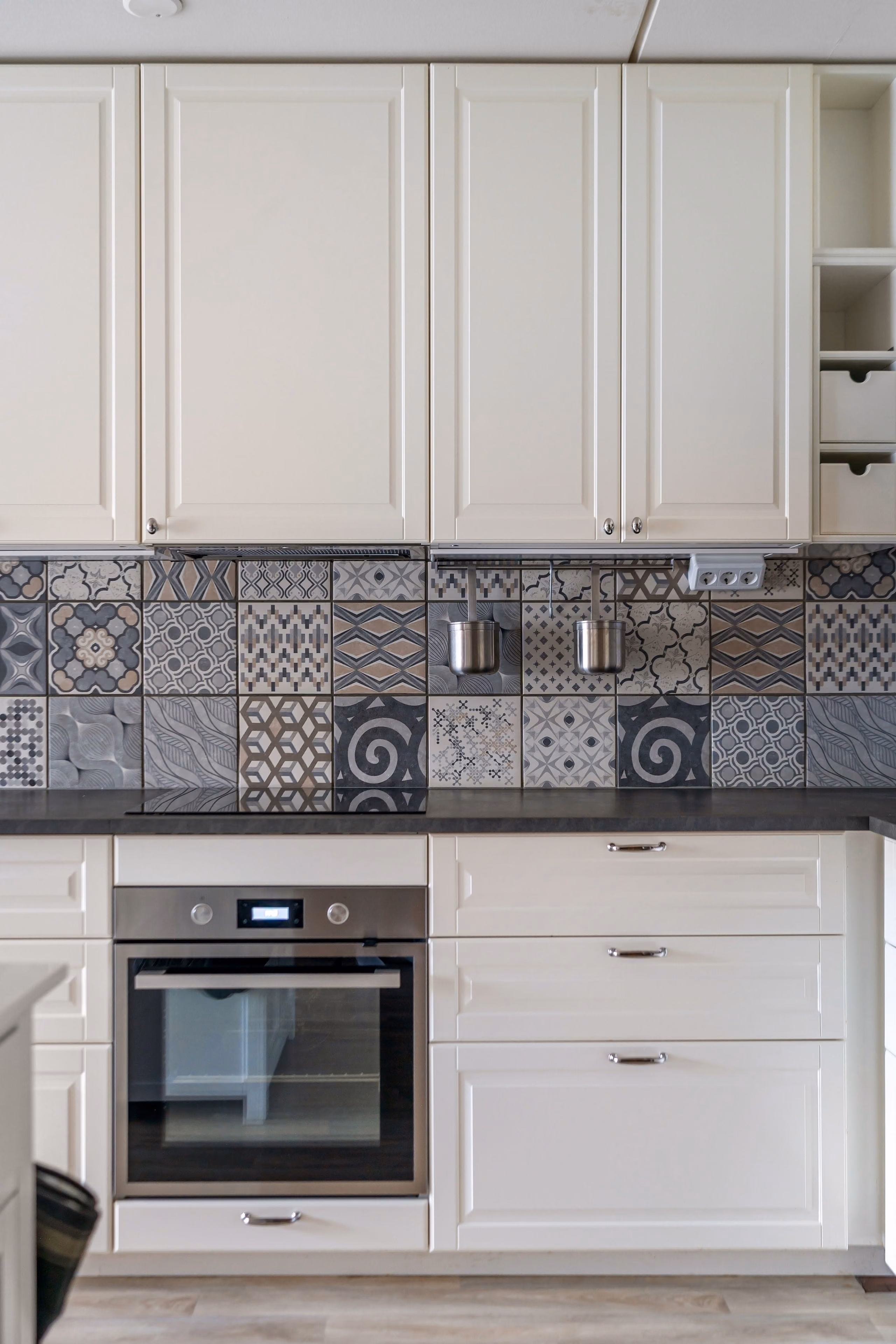 Cream shaker cabinets above a backsplash of grey patterned French-style cement tiles