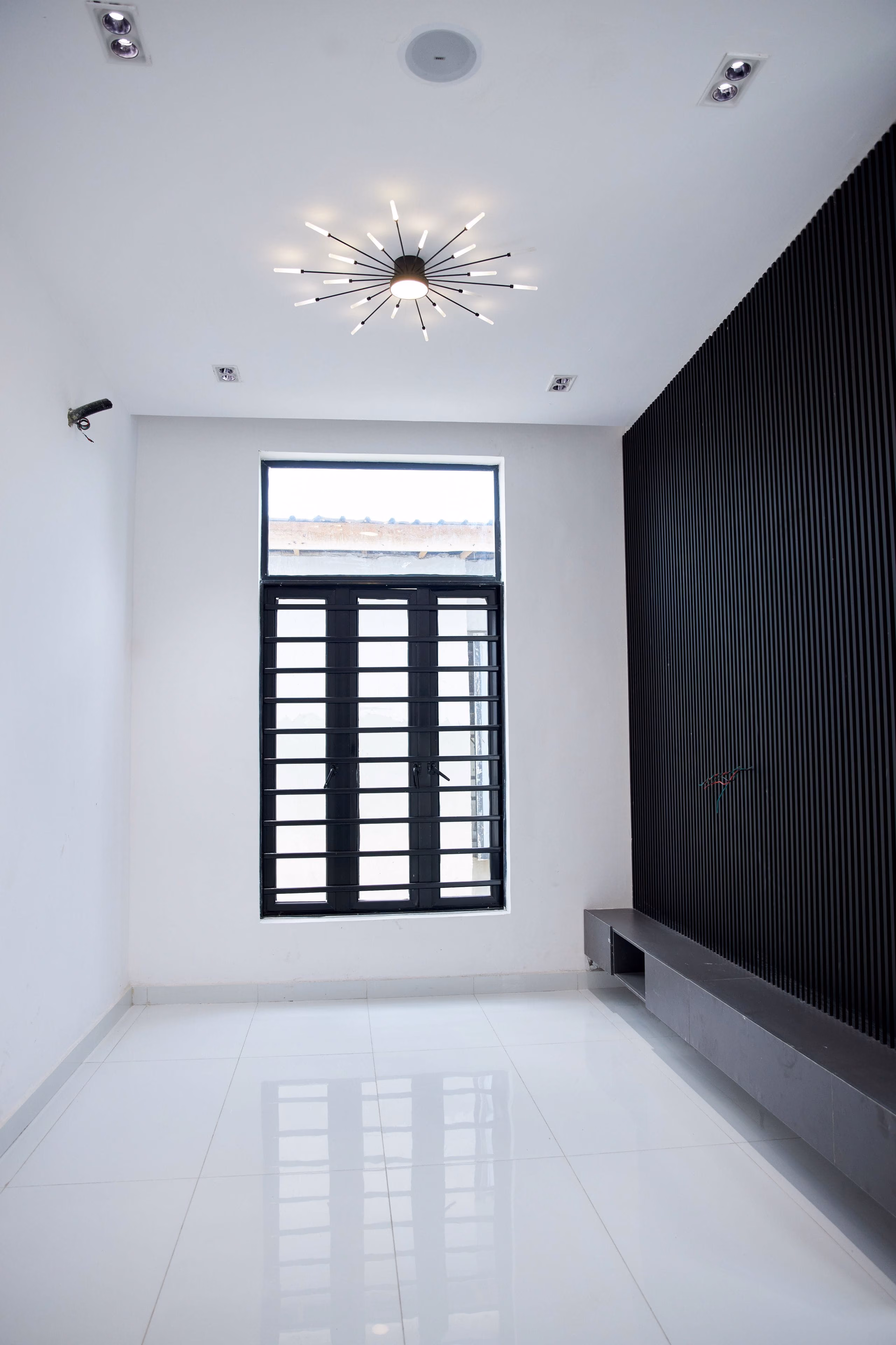 Narrow white room with recessed spotlights, statement ceiling light and glossy tiled floor