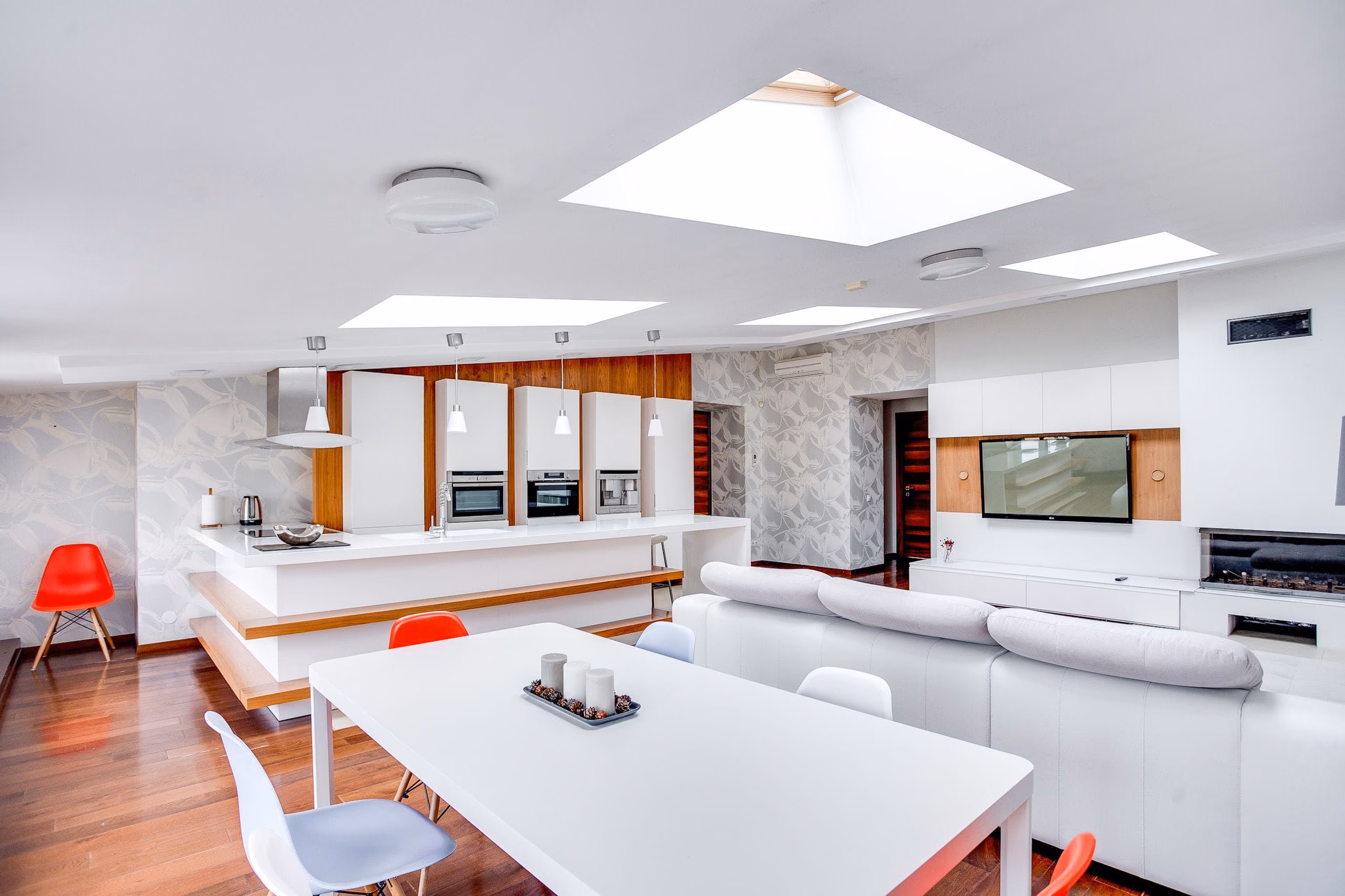 Airy open-plan apartment with white walls, skylights, kitchen island and dining table