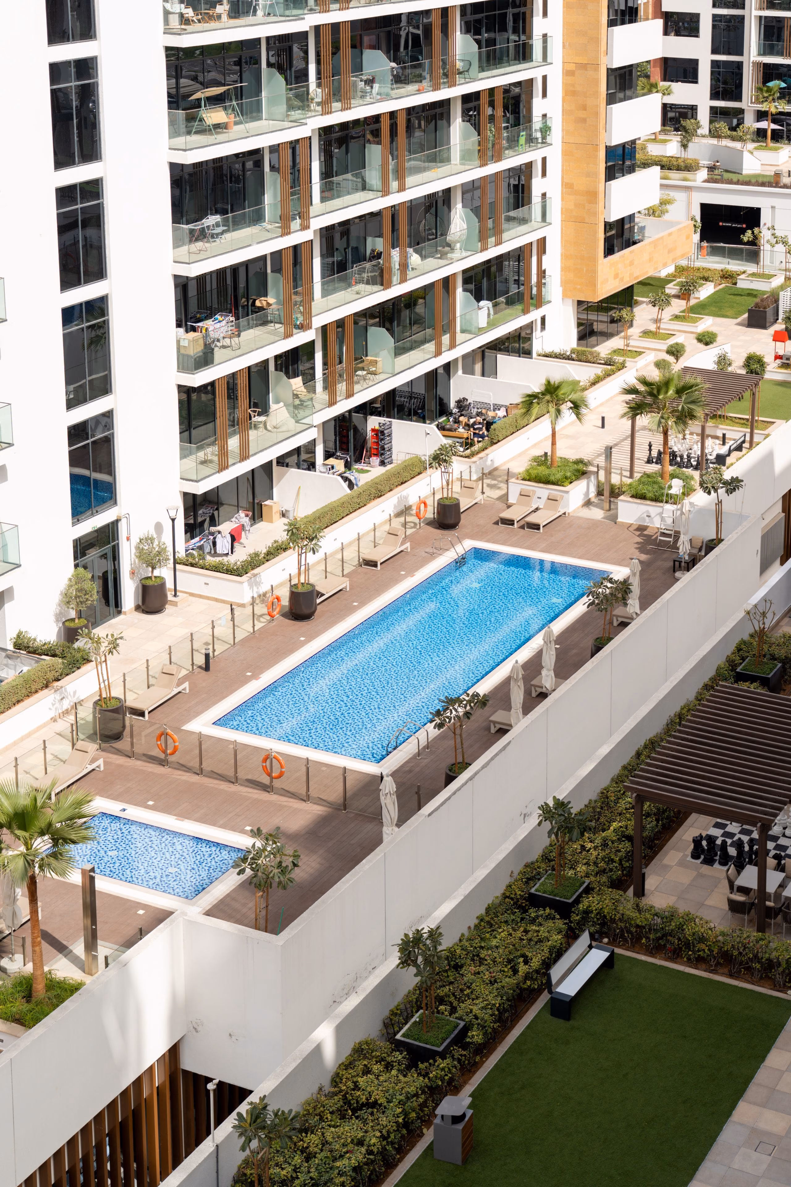 Modern apartment towers overlooking a landscaped courtyard with swimming pools and palms