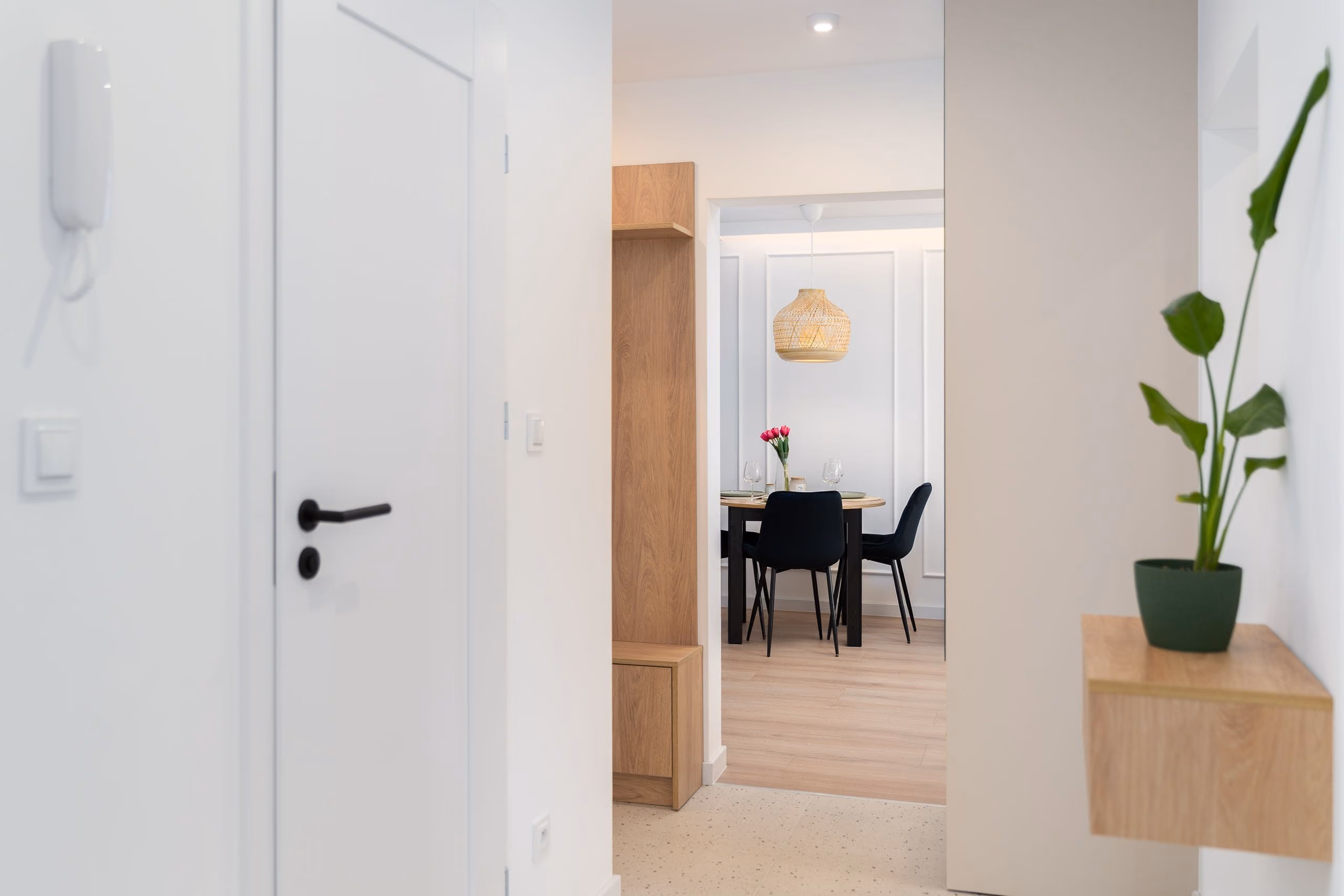 White apartment hallway leading to a dining area with panelled moulding walls