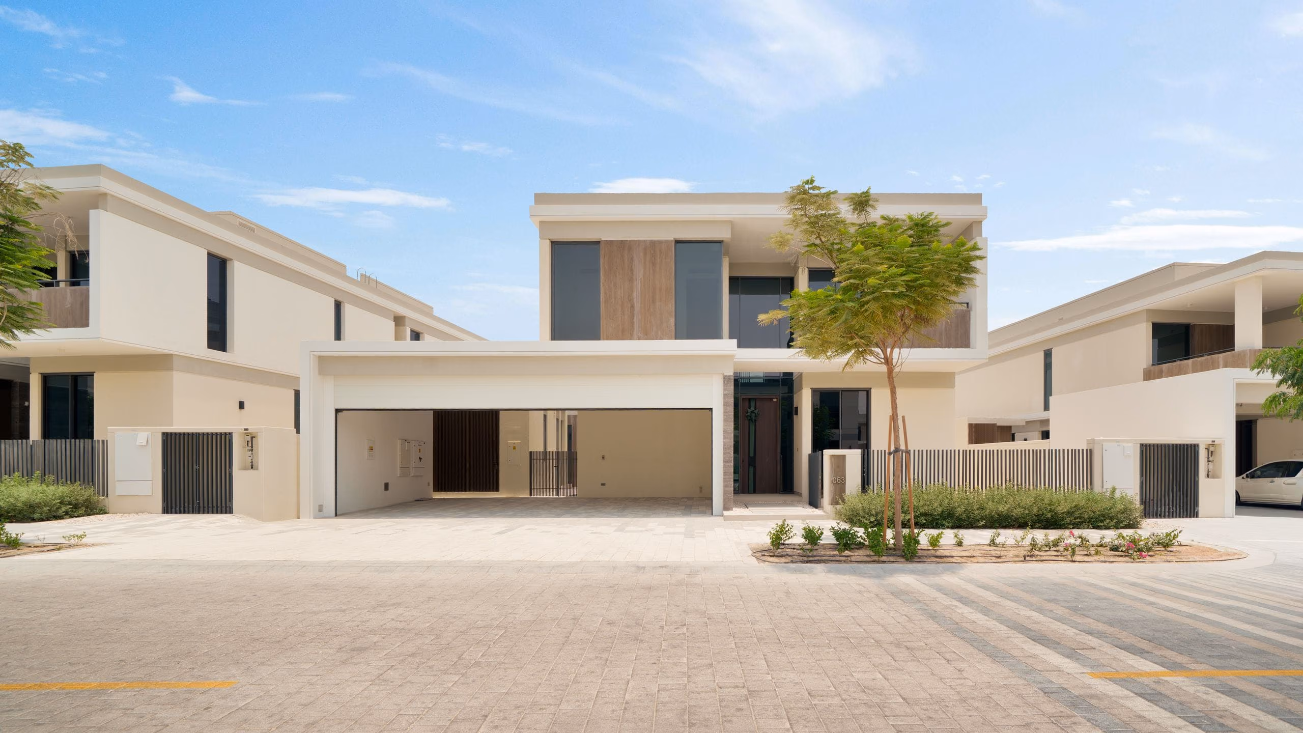 Contemporary beige two-storey villa with a wide open double garage and paved driveway
