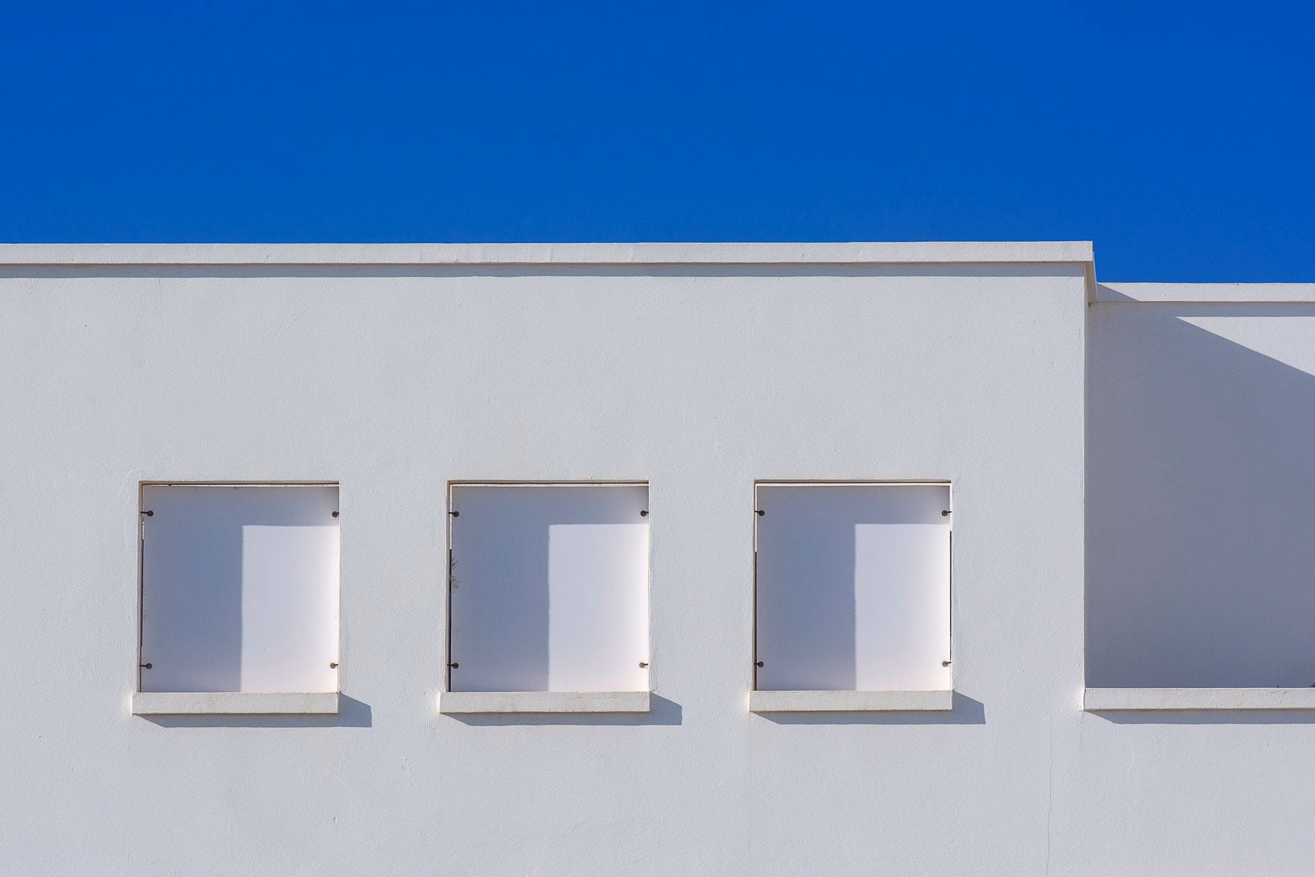 Clean white rendered parapet and roof edge against a deep blue sky