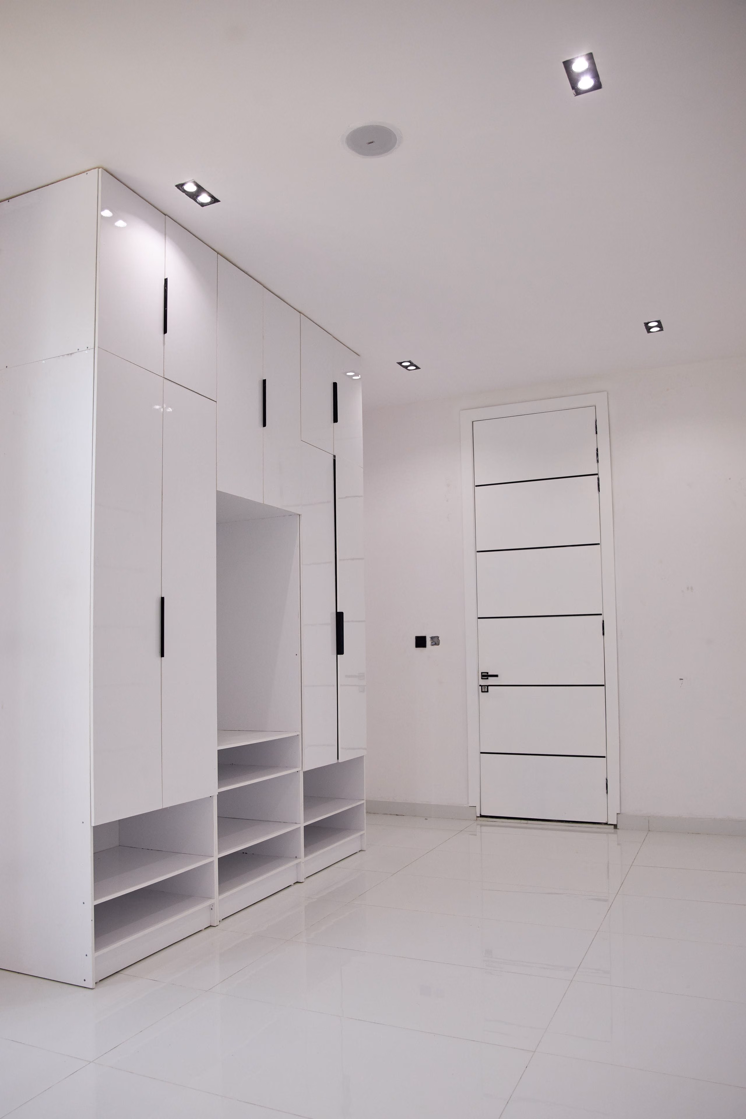 Bright white room with built-in wardrobes, recessed spotlights, flush door and wall switch