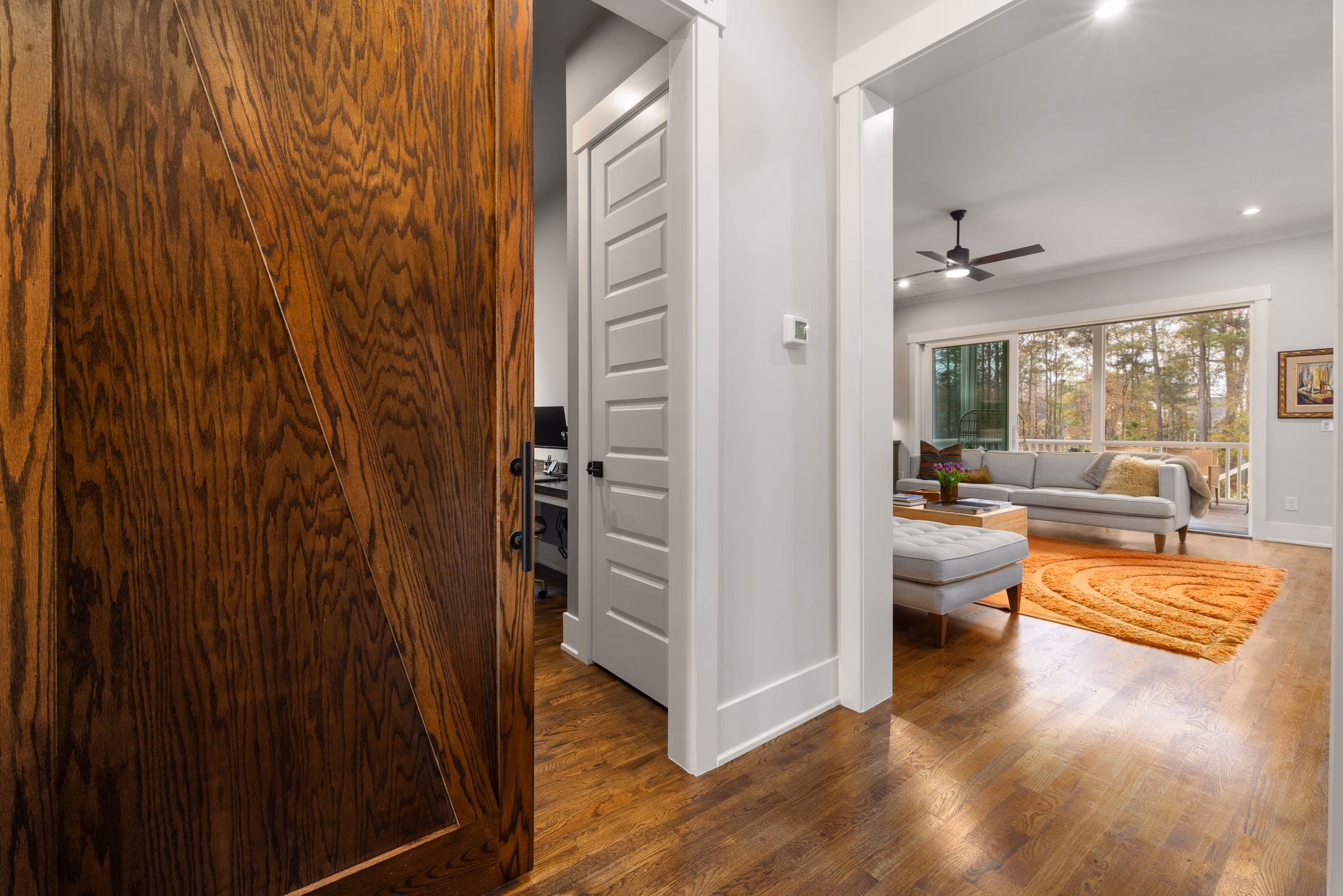 Wooden sliding door on a top track opening into a bright living room with wood floors