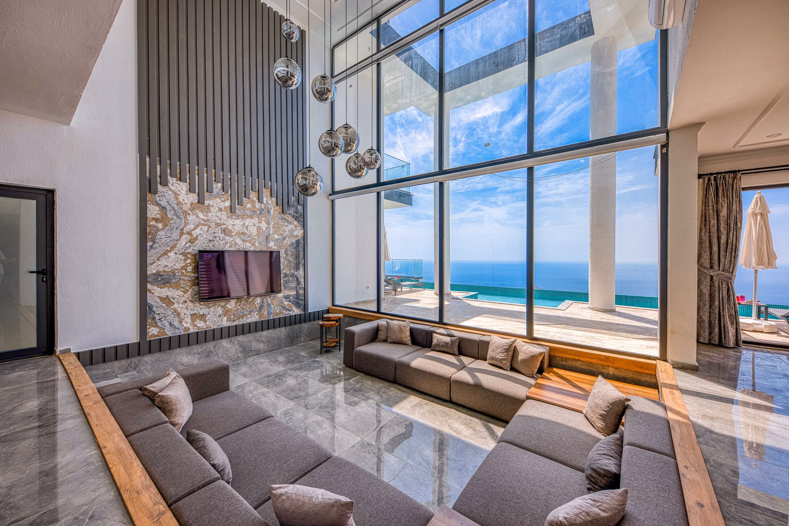Double-height living room with polished marble floor, sunken sofa and floor-to-ceiling sea-view windows