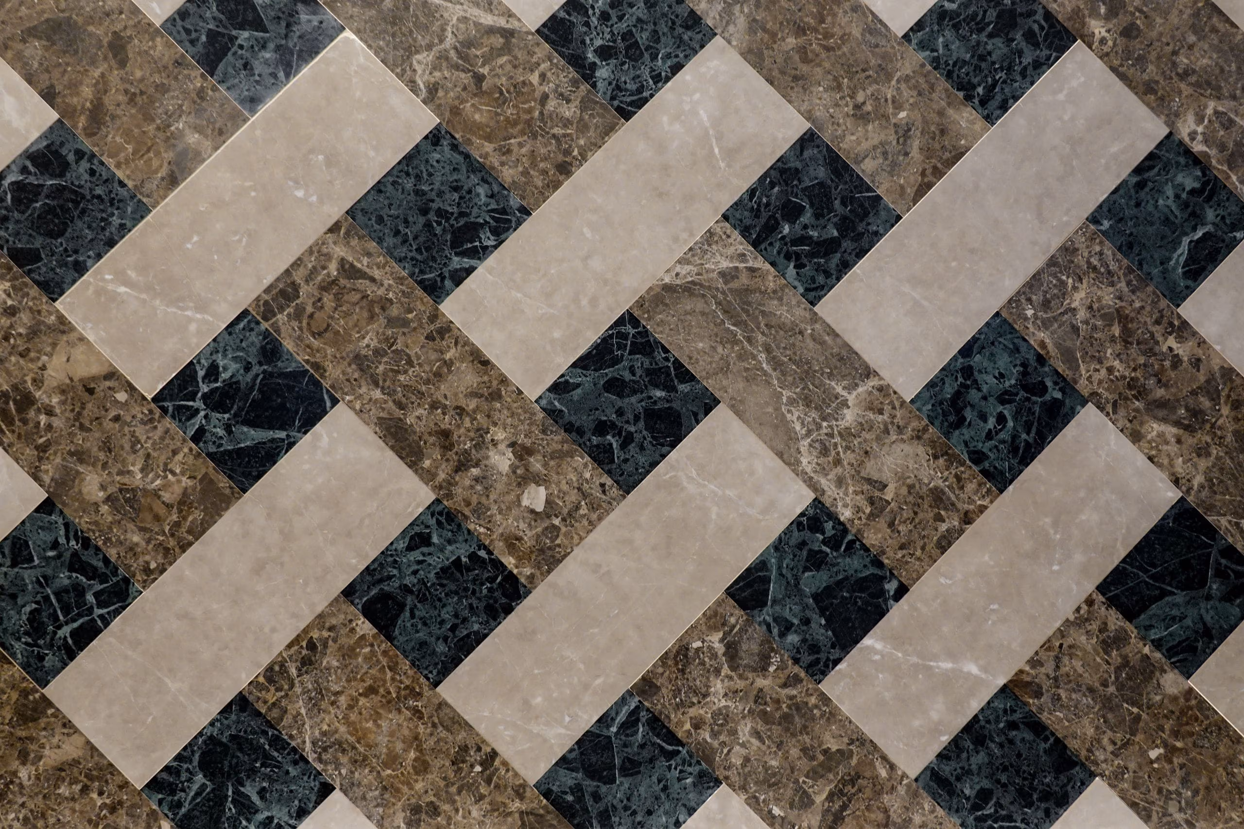 Top view of polished marble floor tiles laid in a woven beige, brown and green pattern