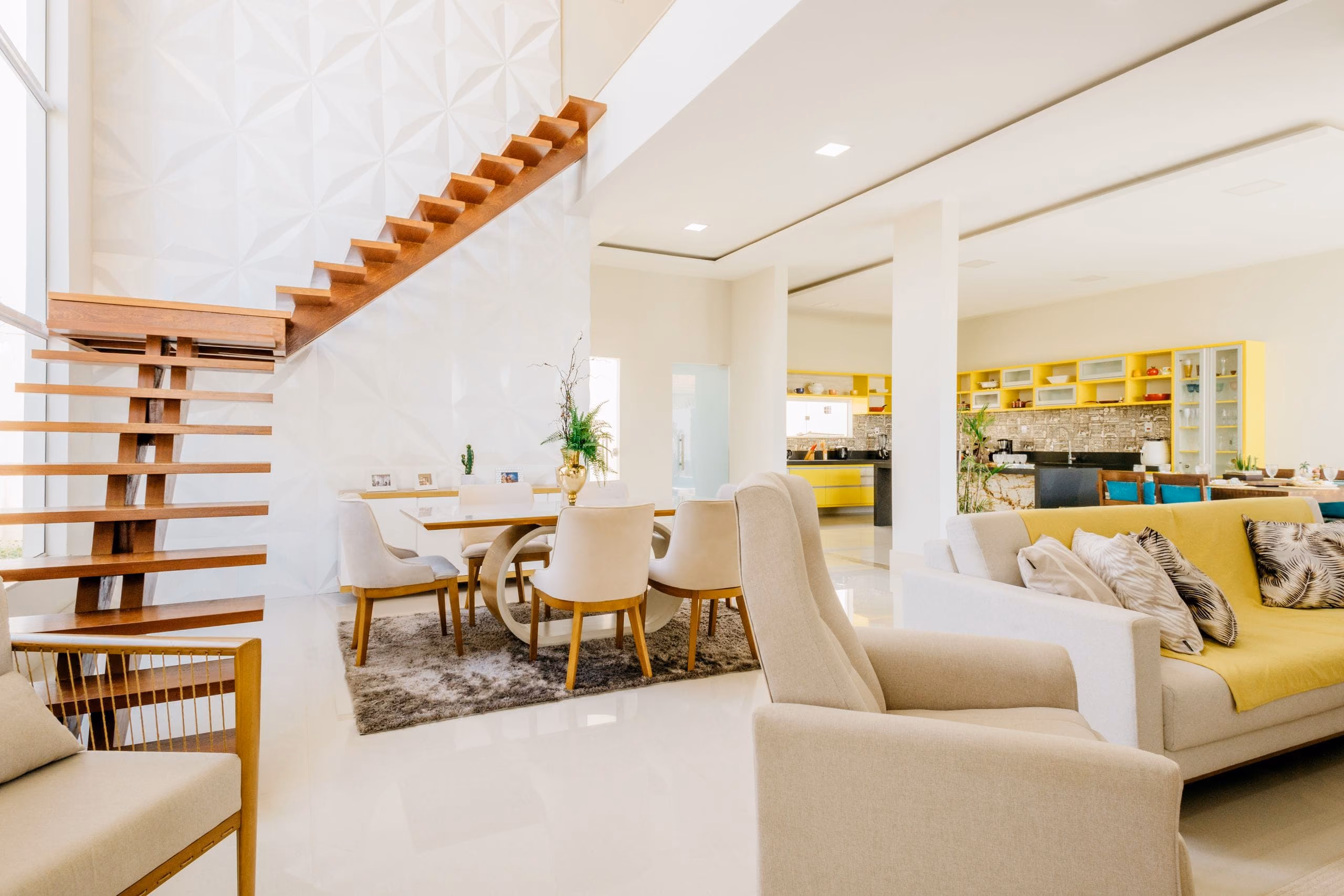 Bright open-plan villa living area with smooth white walls, floating staircase and glossy floor
