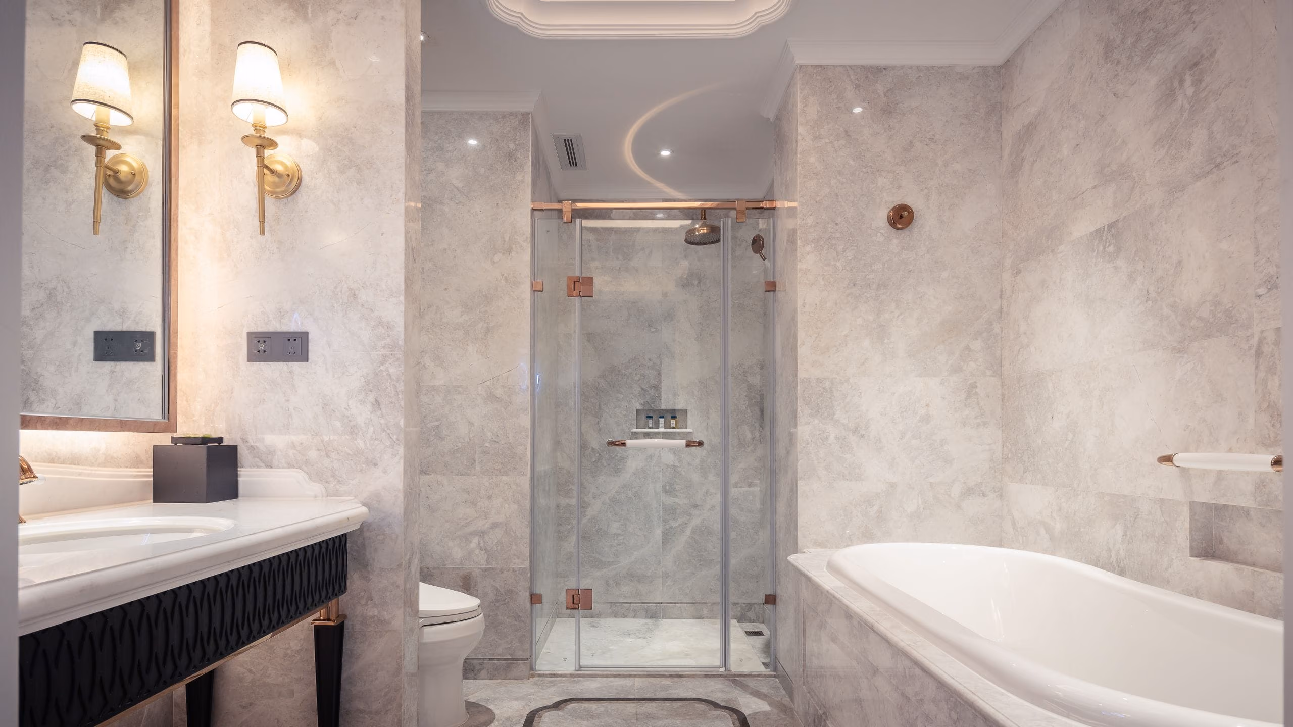 Grey marble-tiled bathroom with glass shower cabin, built-in bathtub and illuminated vanity