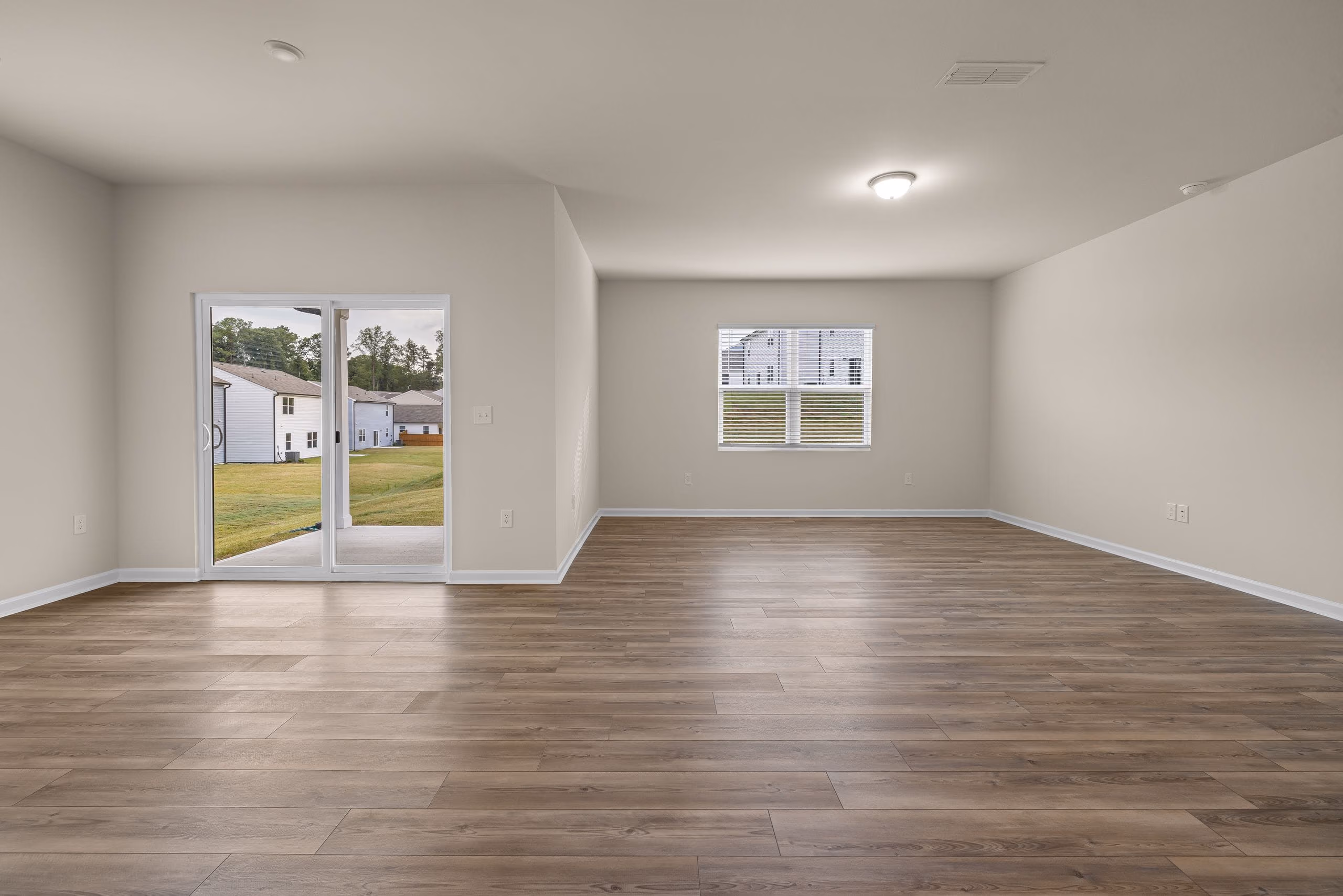 Spacious empty living room with clean painted walls, plank flooring and glass doors