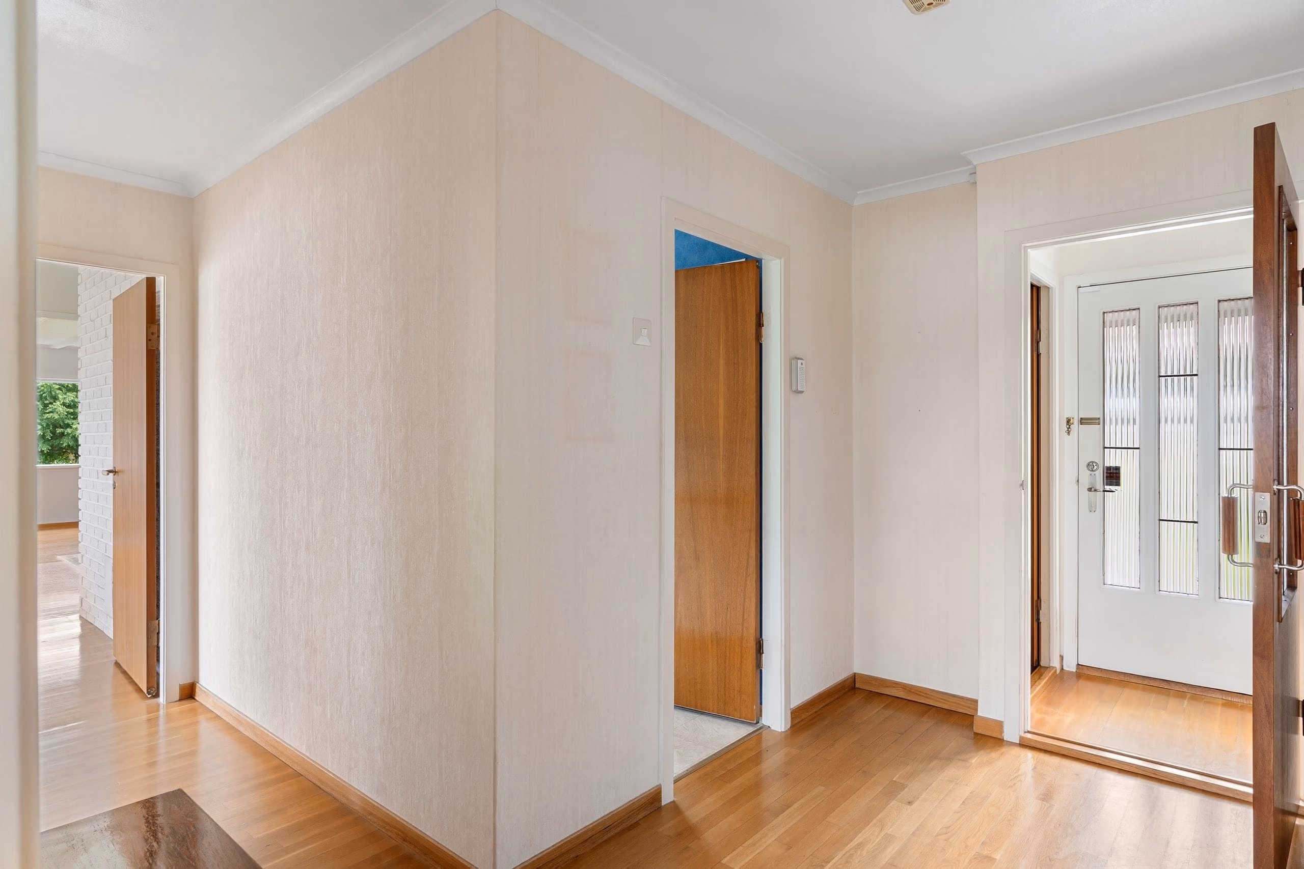 Freshly painted hallway with crown moulding, wooden doors and parquet flooring