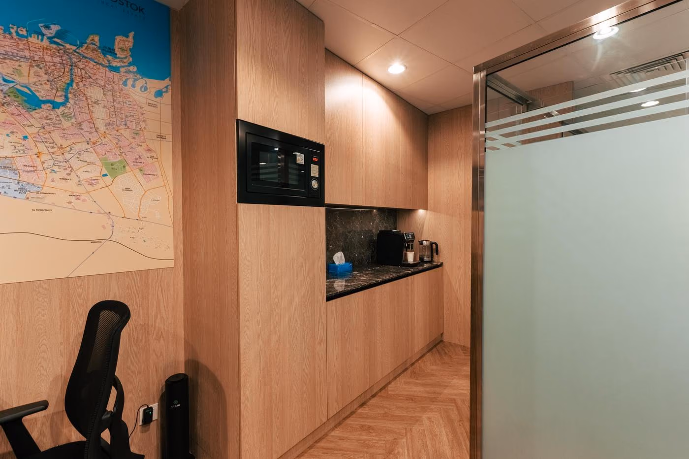 Vostok Real Estate office kitchenette beside an open workspace and wall map